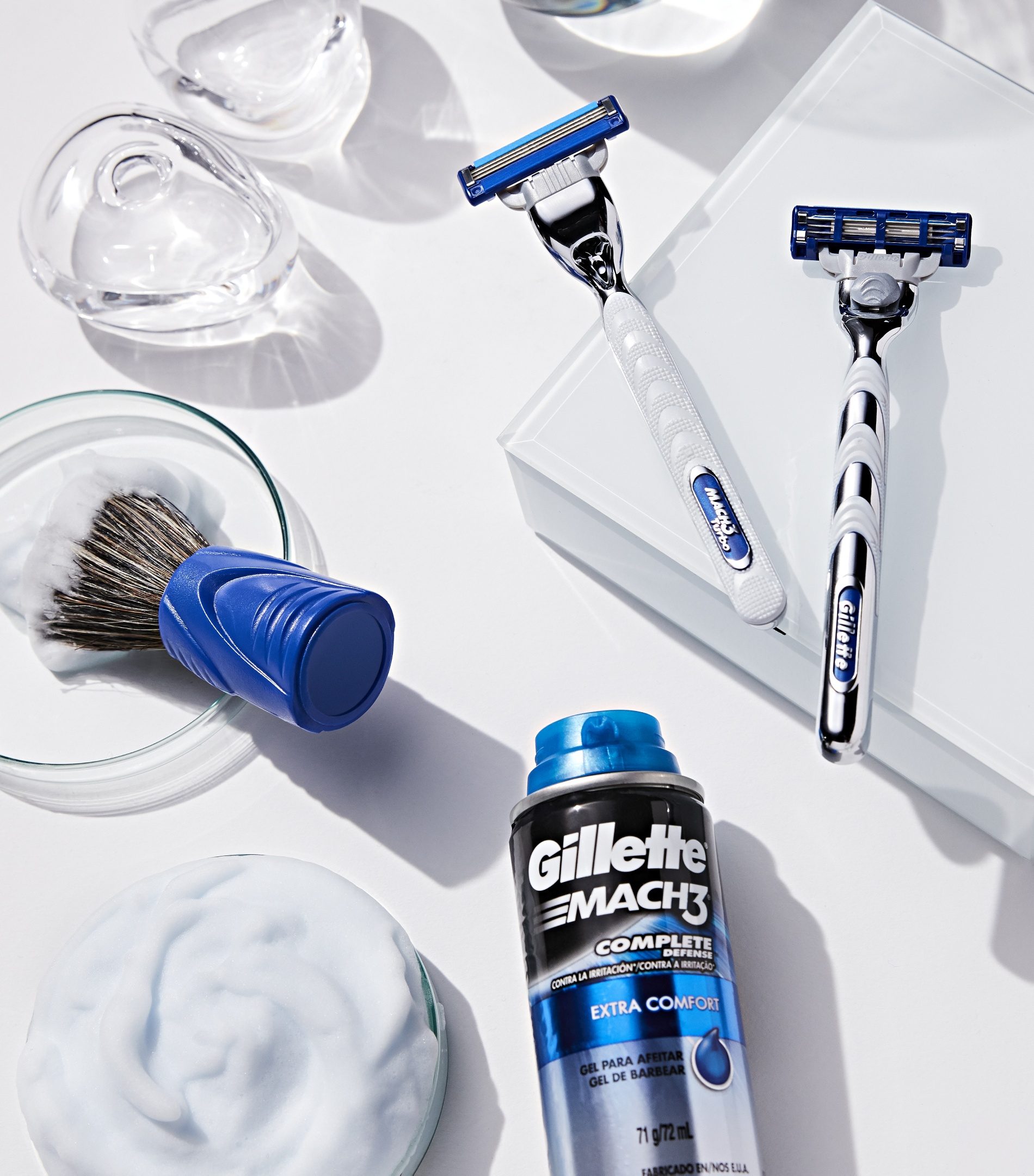 Aparelhos, pincel de barbear azul, espuma e gel Mach3 sobre fundo branco