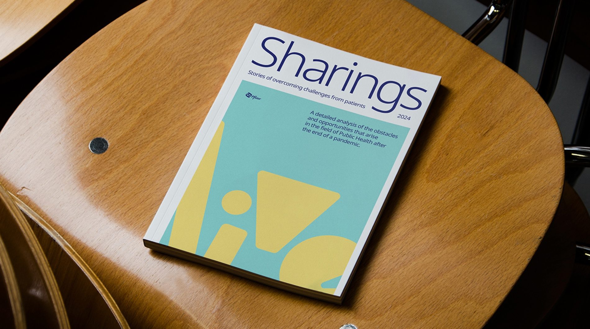 Revista Sharings sobre uma cadeira de madeira, com as formas do Live na capa