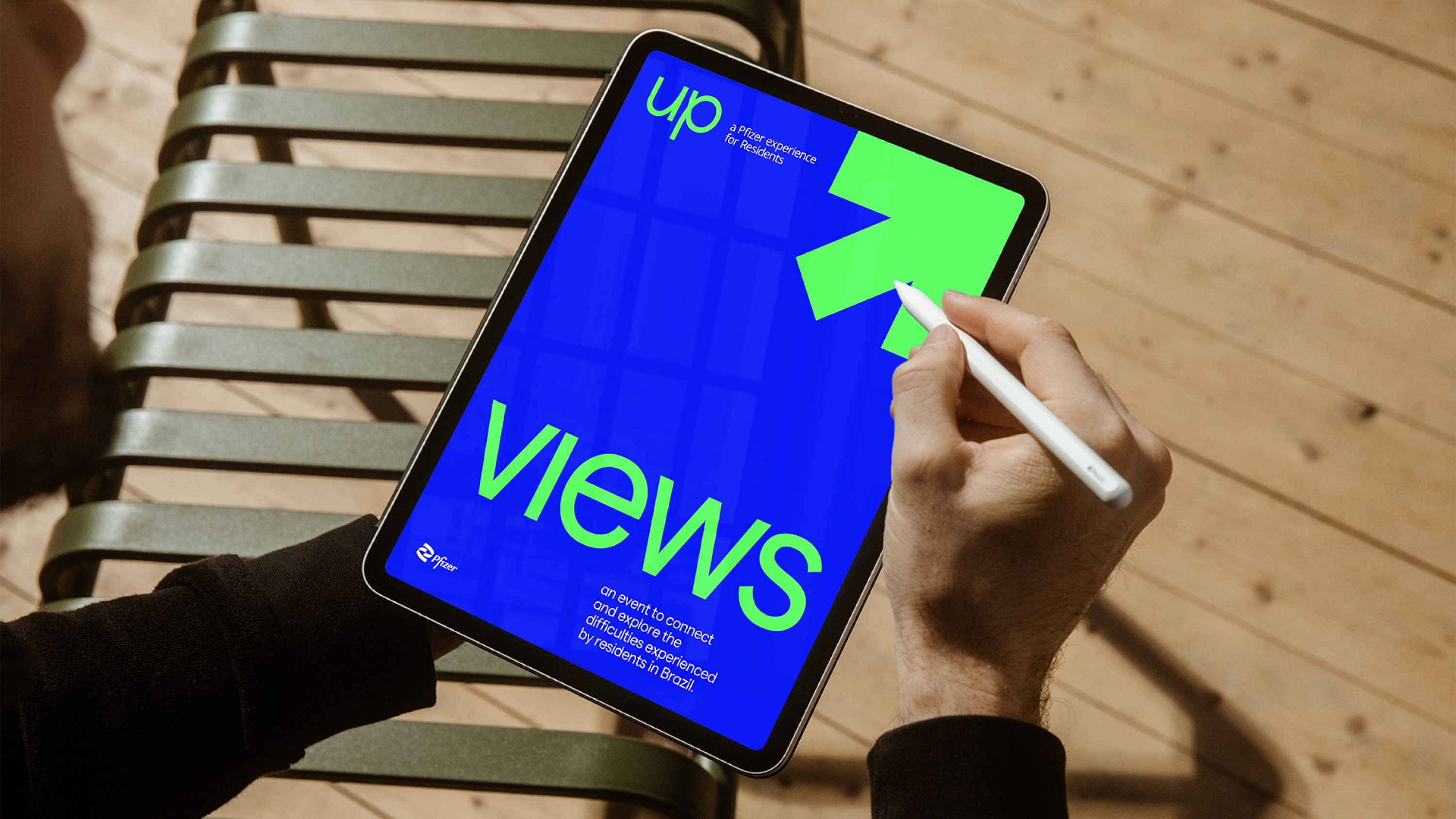 Mão com caneta sobre um tablet com a capa de Views, a seta verde sobre azul